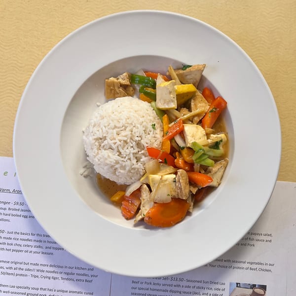 A white bowl of Lao stir-fried tofu and vegetables with a side of white rice.