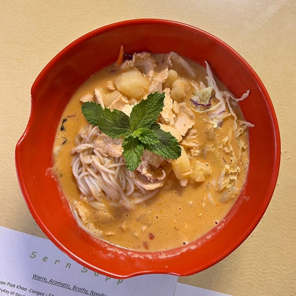 Laos noodle soup with chicken, potatoes, and mint in a red bowl at Sern Sapp Restaurant.