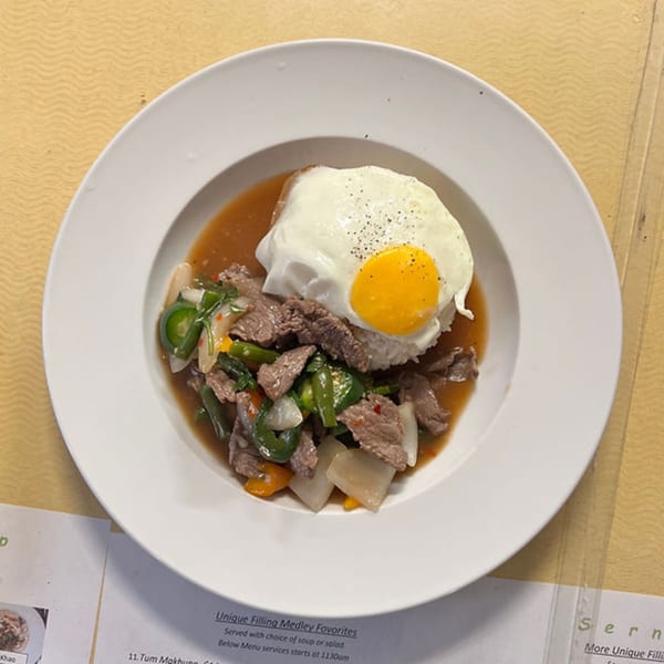 Laos stir-fried beef with peppers and onions, topped with a fried egg and served over rice.